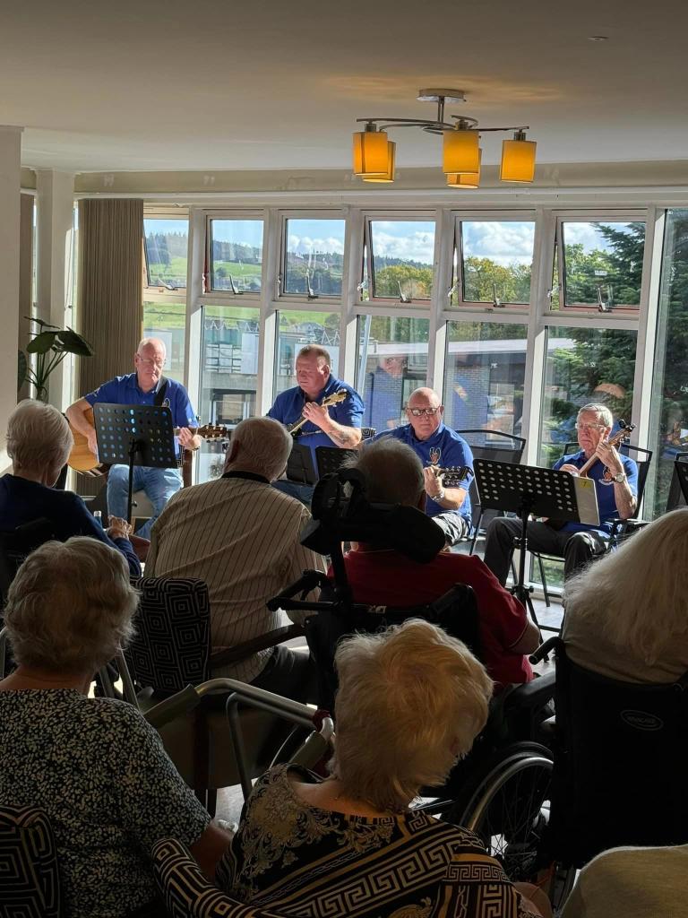 Deeside Care Home residents enjoying a music therapy session with The Plucking Pals.