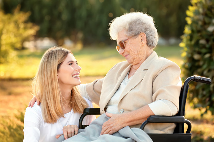 elderly person in a wheelchair outside with family member