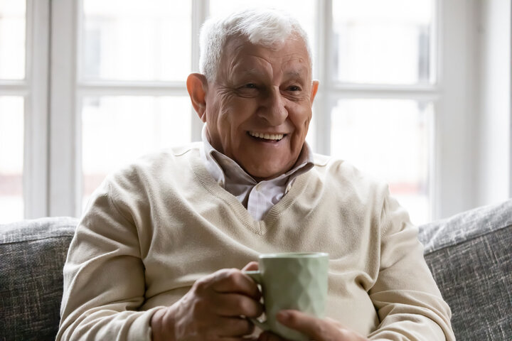 older man smiling with a cup of tea