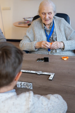 senior woman playing dominoes with young person