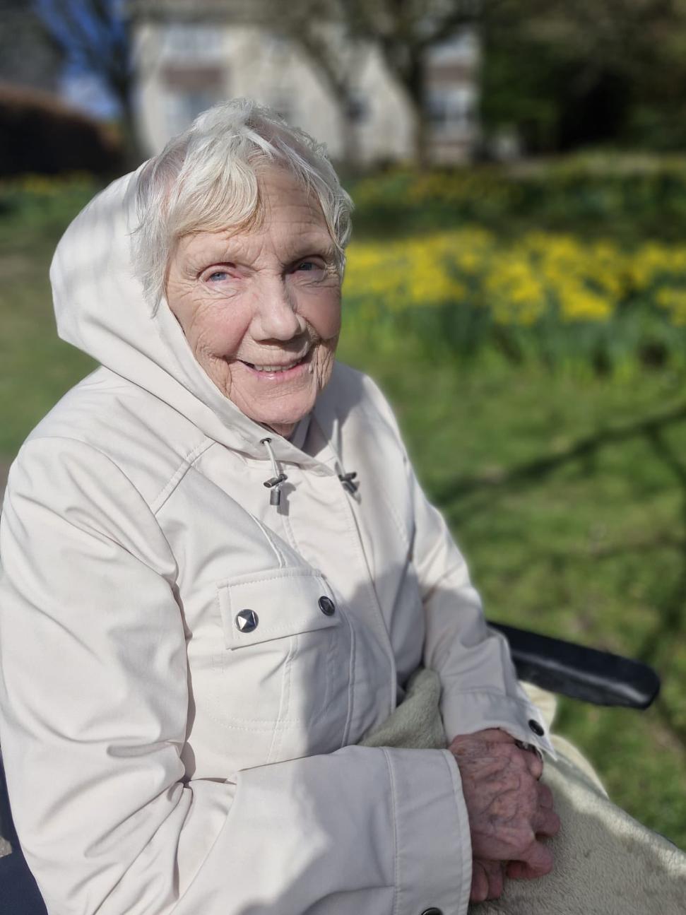 older lady in a coat smiling at the camera